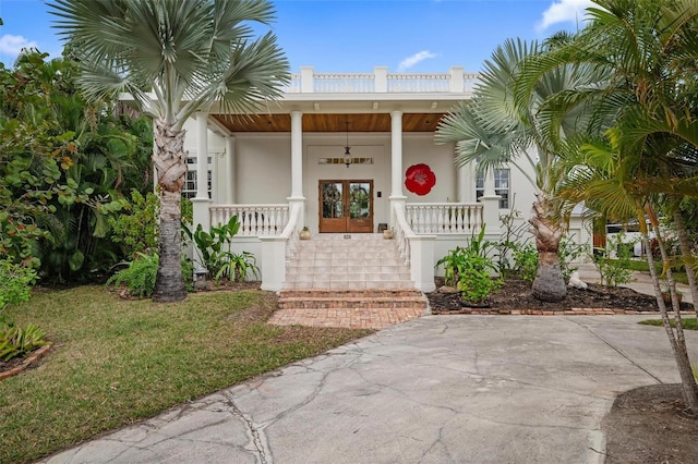 doorway to property featuring covered porch, a yard, and french doors