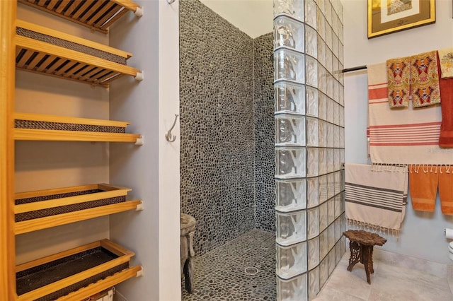 bathroom featuring a tile shower, toilet, and tile patterned floors