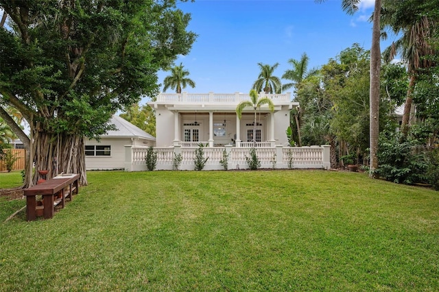 back of property with ceiling fan, french doors, and a yard