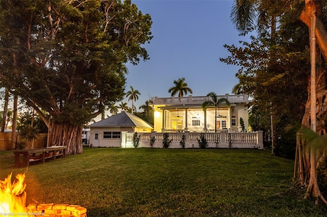 back house at dusk with a yard and a fire pit