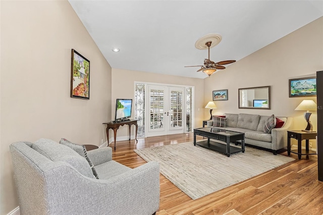 living room with ceiling fan, lofted ceiling, french doors, and light hardwood / wood-style flooring