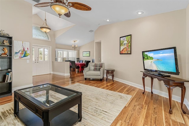 living room with light hardwood / wood-style floors, ceiling fan with notable chandelier, and vaulted ceiling