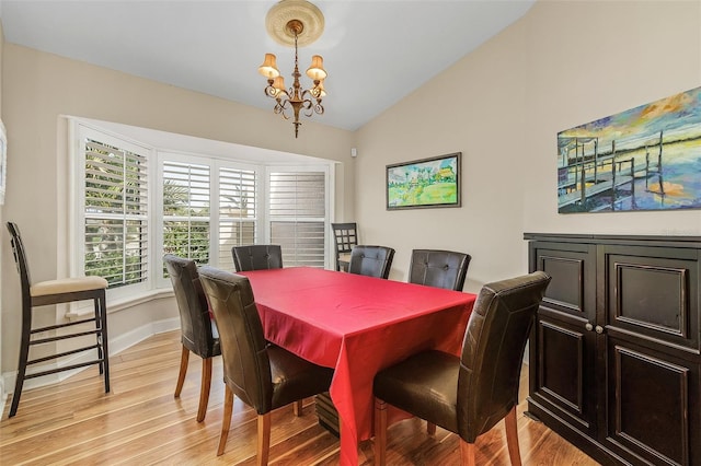 dining room with vaulted ceiling, light wood-type flooring, and an inviting chandelier