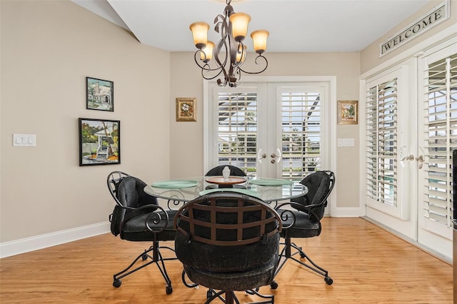 dining space with a chandelier, french doors, and light wood-type flooring