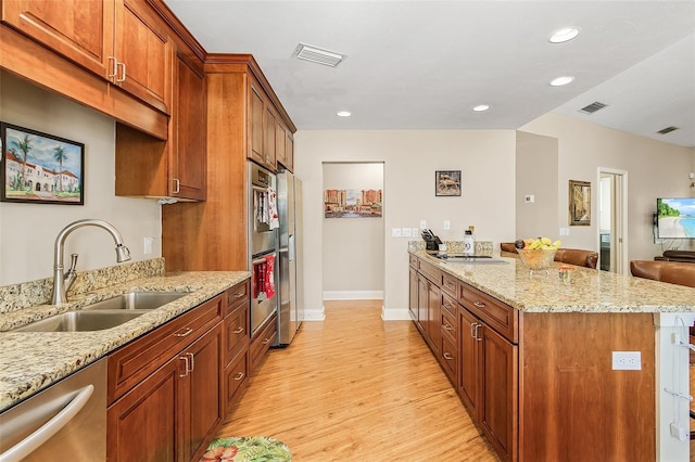 kitchen featuring light stone countertops, appliances with stainless steel finishes, light wood-type flooring, and sink