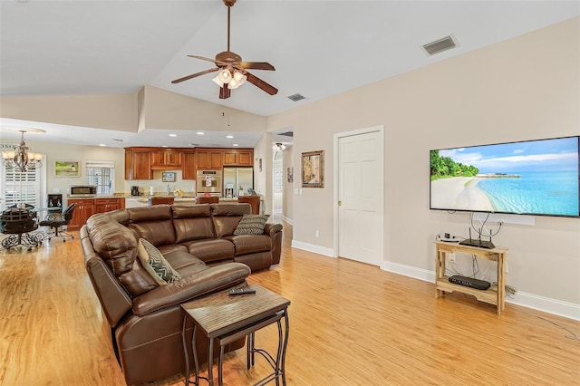 living room with light hardwood / wood-style floors, high vaulted ceiling, and ceiling fan with notable chandelier