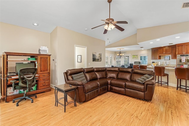 living room with light hardwood / wood-style floors, high vaulted ceiling, and ceiling fan with notable chandelier