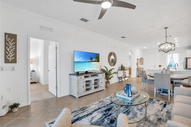 living room with light tile floors, crown molding, and ceiling fan with notable chandelier