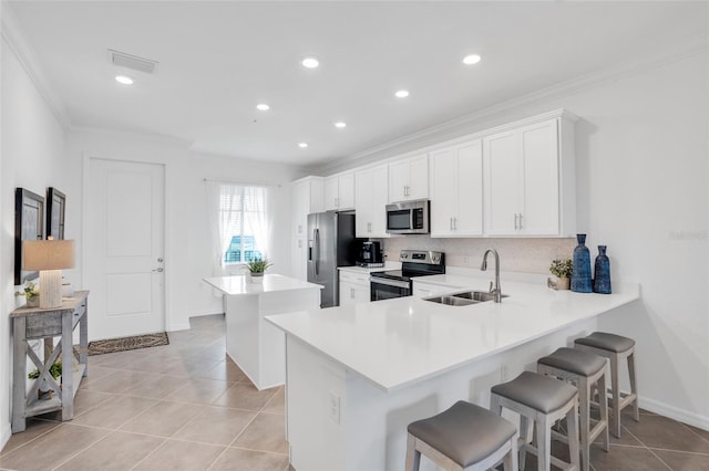 kitchen with stainless steel appliances, light tile floors, white cabinetry, a breakfast bar area, and sink