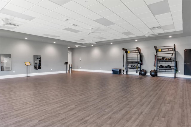 workout area with a paneled ceiling and dark hardwood / wood-style floors