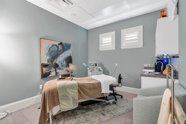 bedroom featuring a drop ceiling and light wood-type flooring