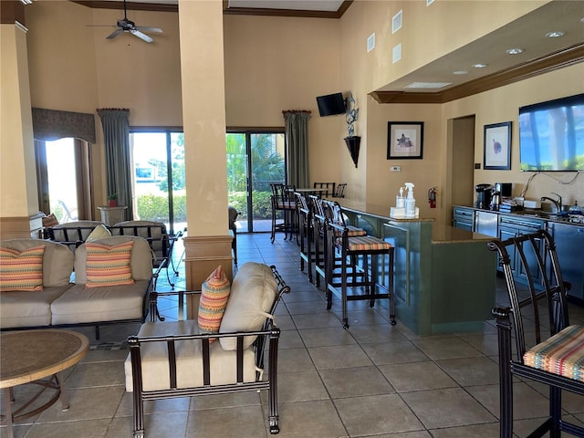 tiled dining area with sink, ceiling fan, crown molding, and a high ceiling