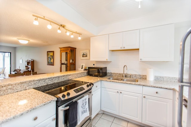 kitchen featuring stainless steel electric range, sink, light tile floors, light stone counters, and white cabinetry