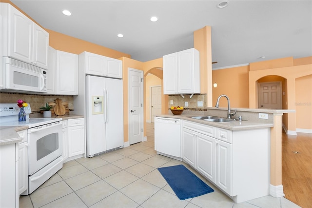 kitchen with sink, white appliances, light tile patterned floors, white cabinetry, and kitchen peninsula