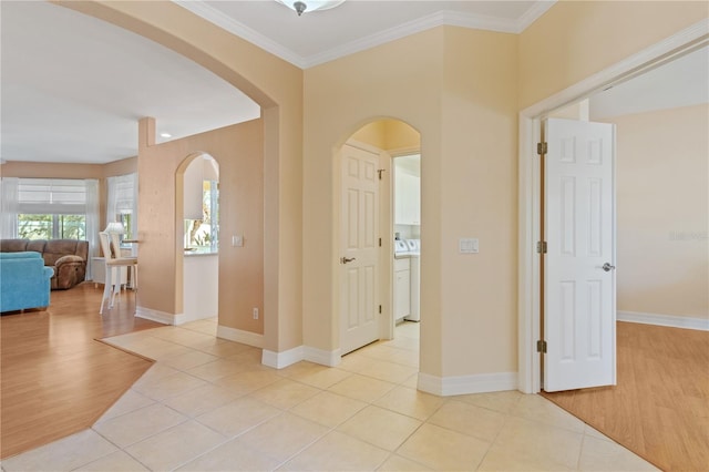 corridor featuring washer / clothes dryer, ornamental molding, and light tile patterned floors