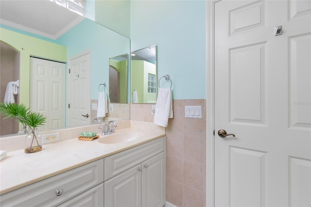 bathroom featuring vanity, ornamental molding, and tile walls