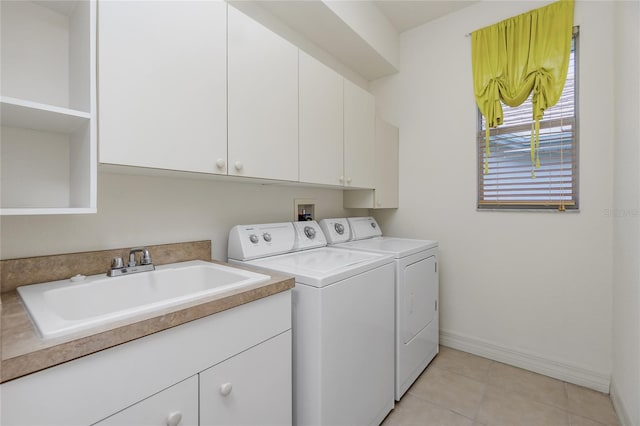 washroom with sink, light tile patterned floors, washer and clothes dryer, and cabinets