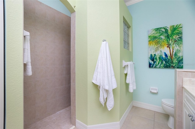 bathroom featuring tile patterned flooring, vanity, a tile shower, and toilet