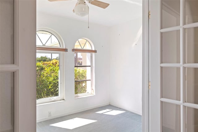 carpeted empty room with a wealth of natural light and ceiling fan