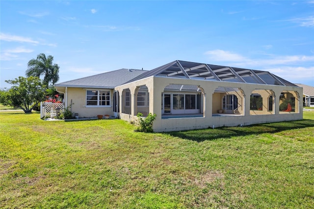 rear view of house with a yard and a lanai