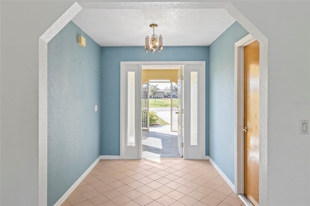 entrance foyer with a textured ceiling, a chandelier, and light tile patterned floors