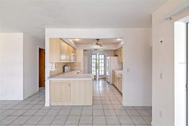 kitchen featuring electric stove, light tile patterned floors, kitchen peninsula, a tray ceiling, and ceiling fan