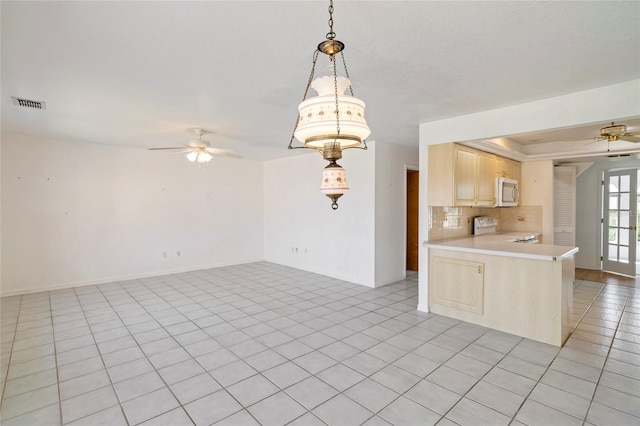 kitchen featuring ceiling fan, backsplash, range, light tile patterned floors, and kitchen peninsula