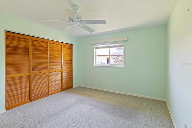 unfurnished bedroom featuring a textured ceiling, a closet, ceiling fan, and carpet floors