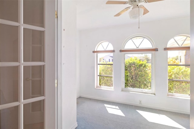 carpeted empty room with ceiling fan and a wealth of natural light