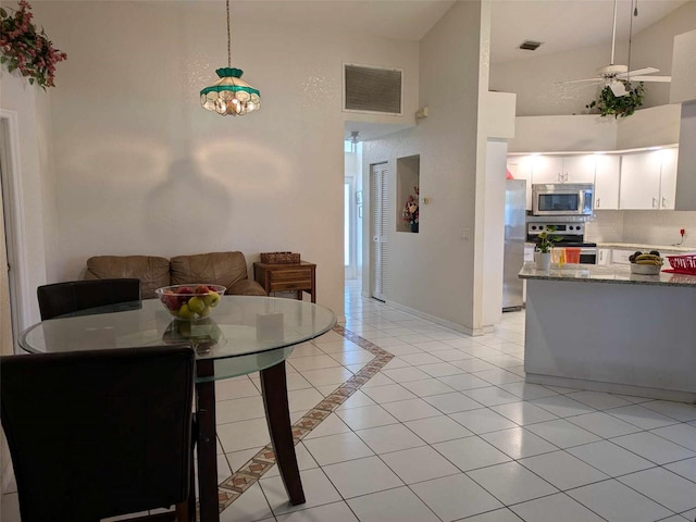 dining space featuring light tile patterned flooring, ceiling fan, and high vaulted ceiling