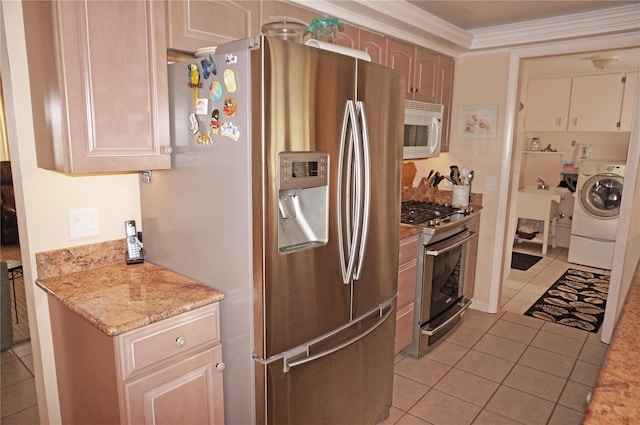 kitchen with light tile flooring, appliances with stainless steel finishes, light stone counters, crown molding, and washer / clothes dryer