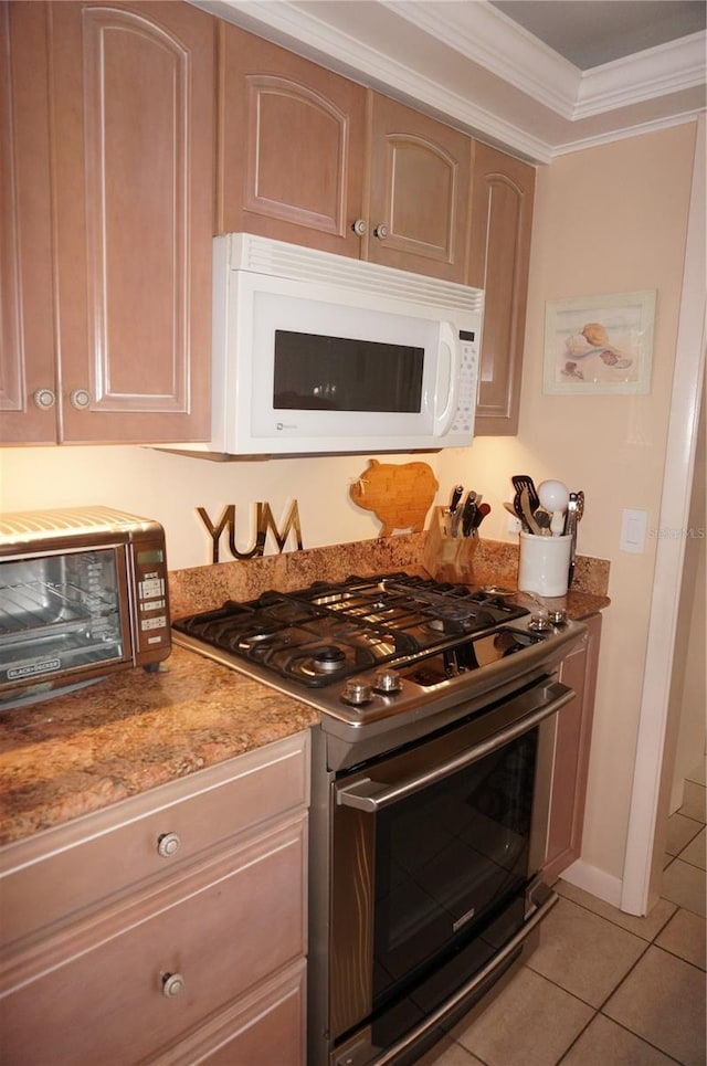 kitchen with light tile floors, gas range oven, stone counters, and ornamental molding