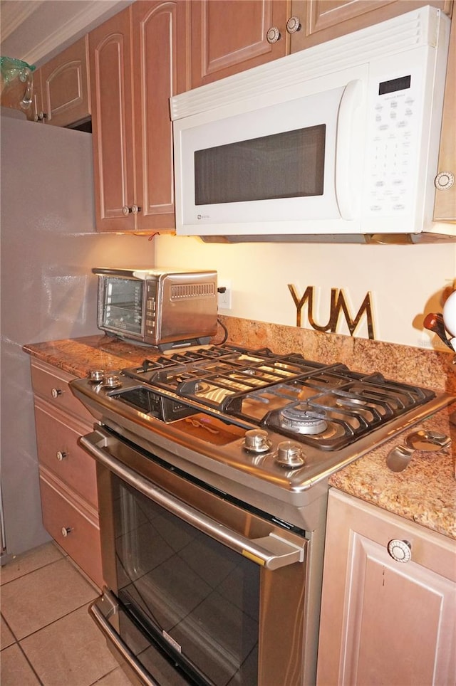 kitchen featuring light tile floors, light stone countertops, and range with gas stovetop