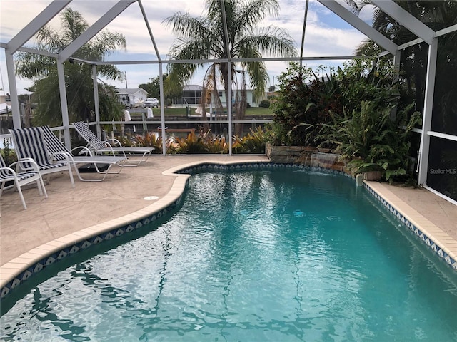 view of swimming pool featuring a patio and glass enclosure