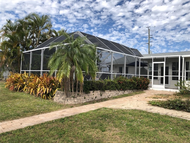 view of side of property featuring a lawn and glass enclosure