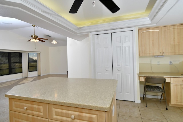 kitchen with light tile floors, a raised ceiling, light brown cabinetry, and ceiling fan