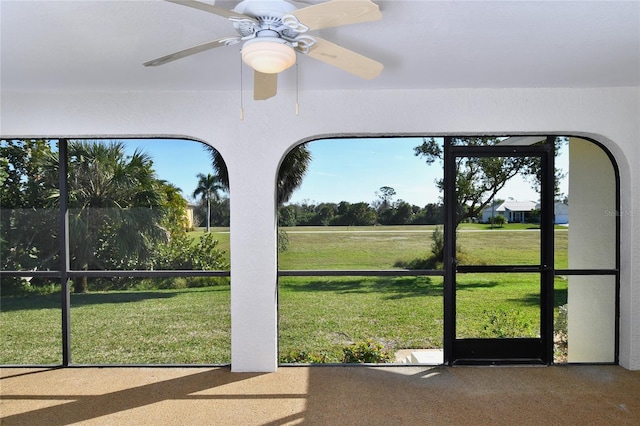 unfurnished sunroom featuring ceiling fan