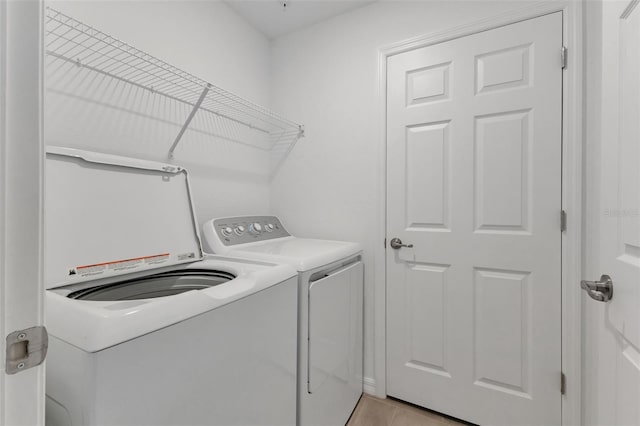 clothes washing area with light tile patterned flooring and washing machine and dryer