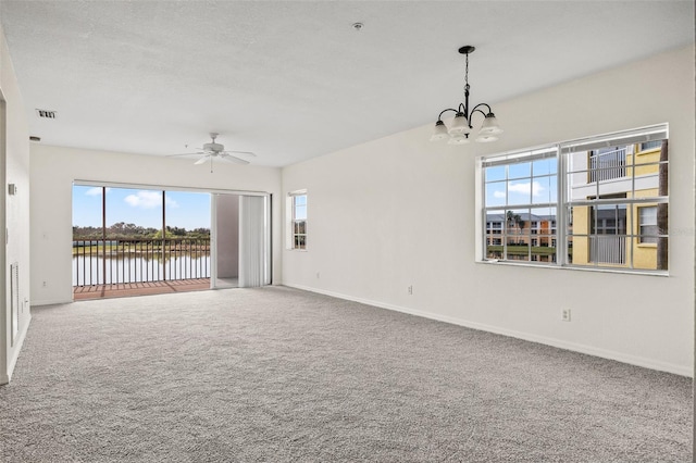 carpeted spare room with a textured ceiling, ceiling fan with notable chandelier, and a wealth of natural light