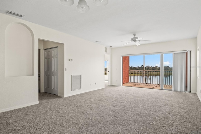 unfurnished living room with a water view, light colored carpet, and ceiling fan