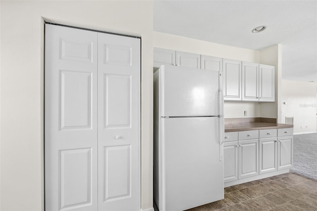 kitchen with white cabinets, light tile flooring, and white refrigerator