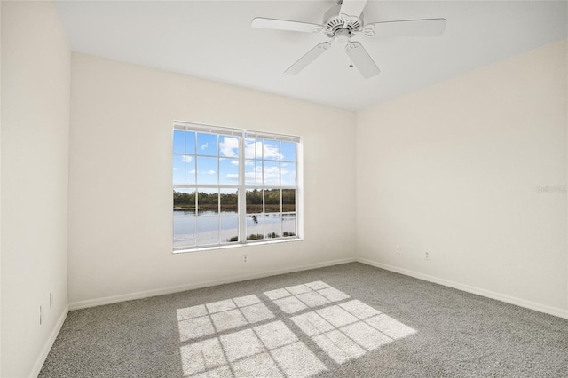 carpeted spare room with a water view and ceiling fan