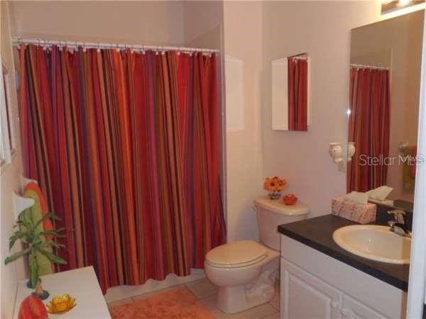 bathroom with oversized vanity, toilet, and tile floors