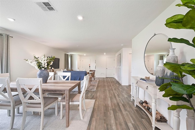 dining space featuring dark hardwood / wood-style flooring and a textured ceiling