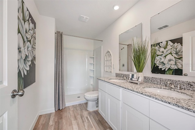 bathroom featuring hardwood / wood-style flooring, toilet, vanity, and walk in shower