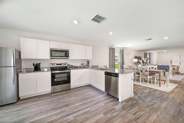 kitchen featuring white cabinetry, appliances with stainless steel finishes, kitchen peninsula, and light hardwood / wood-style floors