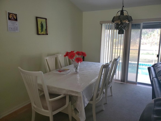 dining room featuring plenty of natural light, dark colored carpet, and an inviting chandelier