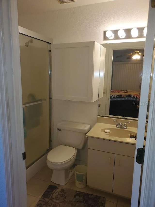 bathroom featuring toilet, tile flooring, walk in shower, and vanity