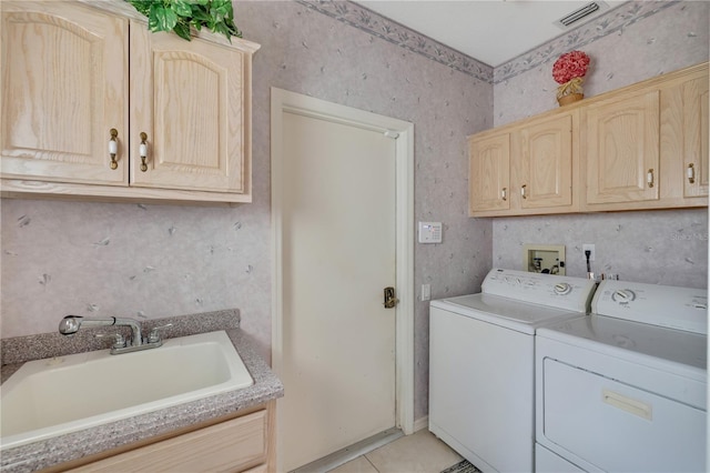 clothes washing area with cabinets, light tile patterned floors, sink, and washing machine and clothes dryer