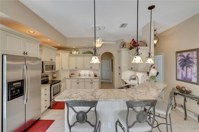 kitchen featuring a kitchen breakfast bar, sink, hanging light fixtures, kitchen peninsula, and stainless steel appliances